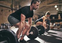 Man and woman lifting barbells in gym.