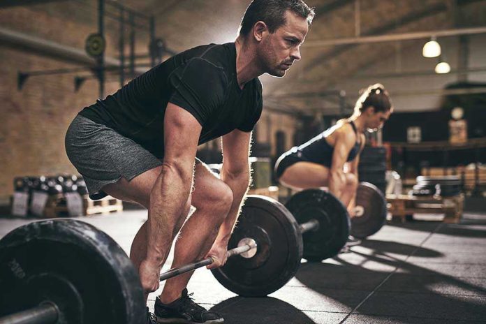 Man and woman lifting barbells in gym.