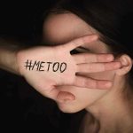 Hand with #MeToo covering face.