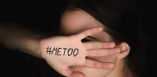 Hand with #MeToo covering face.
