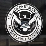 Immigration Agents Shoot Driver – Justified? U.S. Department of Homeland Security emblem on wall.