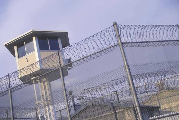 104591603-1 Guard tower behind barbed wire fence in a prison.