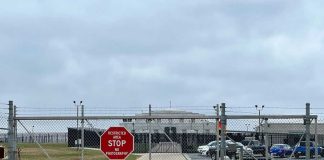 Chain-link fence with Restricted Area Stop No Photography sign.