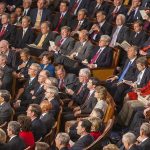 Intelligence Officials BURIED COVID Evidence — Shocking Allegations Audience of officials sitting and reading documents in auditorium.
