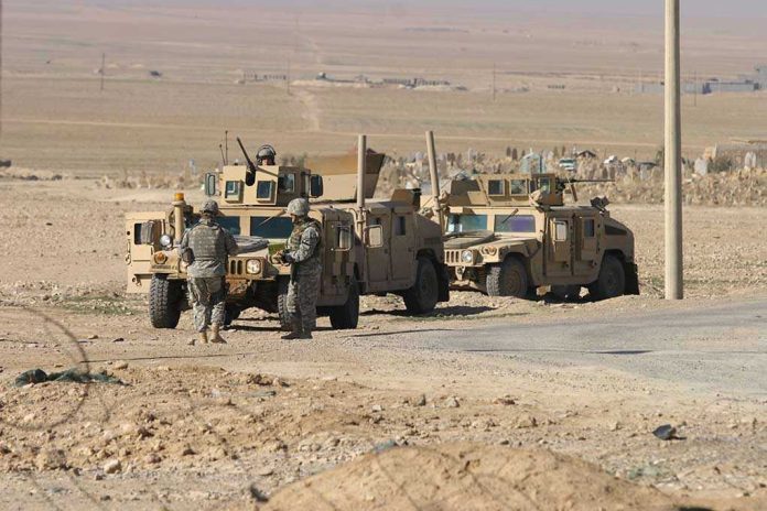 Soldiers standing near armored vehicles in desert terrain.