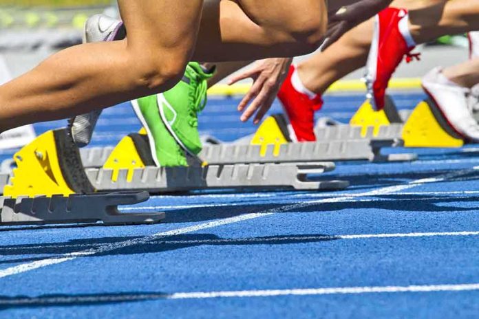shutterstock_104693087 Athletes starting a sprint from starting blocks on a blue track