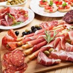 A beautifully arranged charcuterie board featuring various cured meats and olives