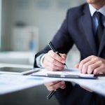 SHOCKING Rumors Fail: Mysterious Weapons Rumor on Reporter DISMISSED! A man in a suit writing notes at a desk with documents and a tablet