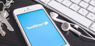 UK Agency Turns Heat on X! Smartphone displaying the Twitter logo next to keys and earphones on a desk
