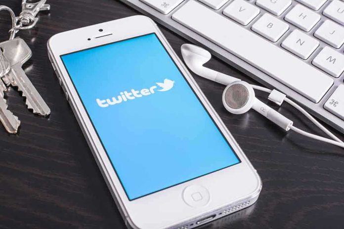 shutterstock_170614799 Smartphone displaying the Twitter logo next to keys and earphones on a desk