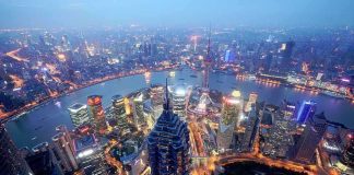 Weak April Data Sparks China Anxiety! Aerial view of Shanghais skyline at night with illuminated buildings and a river
