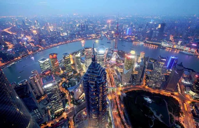 shutterstock_219709417 Aerial view of Shanghais skyline at night with illuminated buildings and a river
