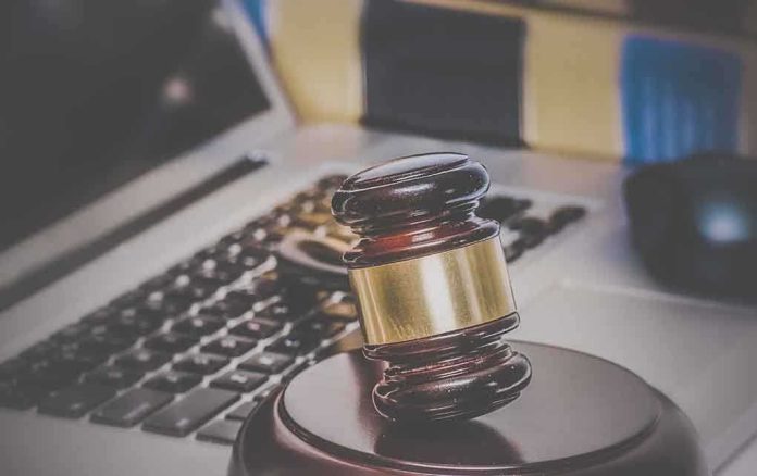 A wooden gavel resting on a desk with a laptop in the background