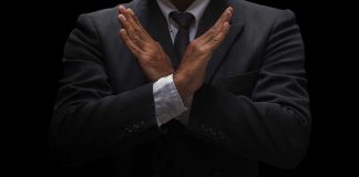 A man in a suit crossing his arms in a gesture of refusal or rejection