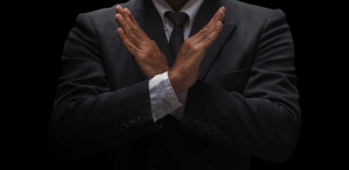 A man in a suit crossing his arms in a gesture of refusal or rejection