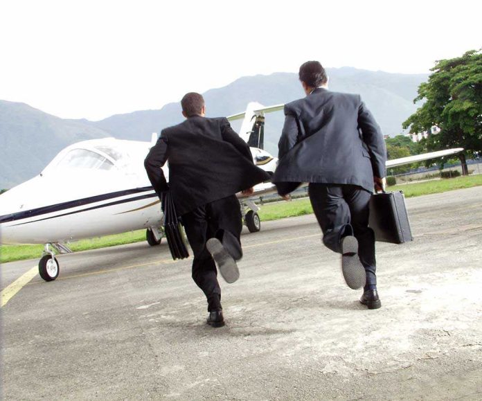 Two businessmen in suits running towards a private jet at an airport