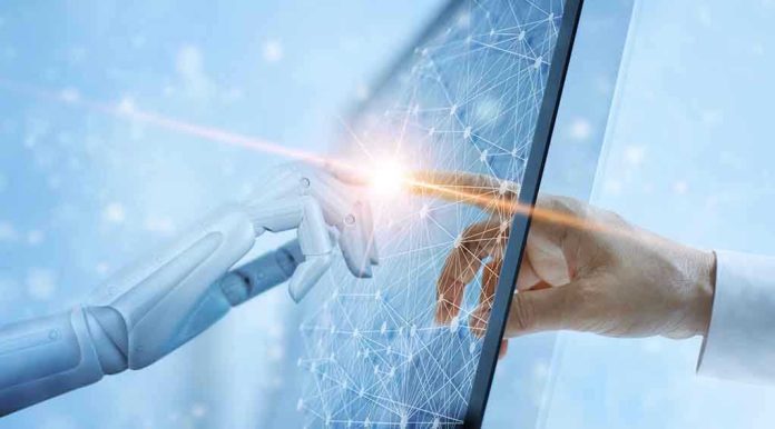 1169699968 Robotic and human hands touching through a screen.