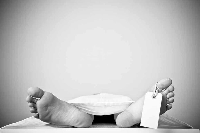 570406495 Bare feet with toe tag on body covered by sheet.