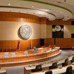 Sovereignty Shock: Pentagon Tie-Up Exposed Interior view of a government chamber with wooden paneling and seating