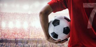 Soccer player holding a ball in a stadium with a cheering crowd