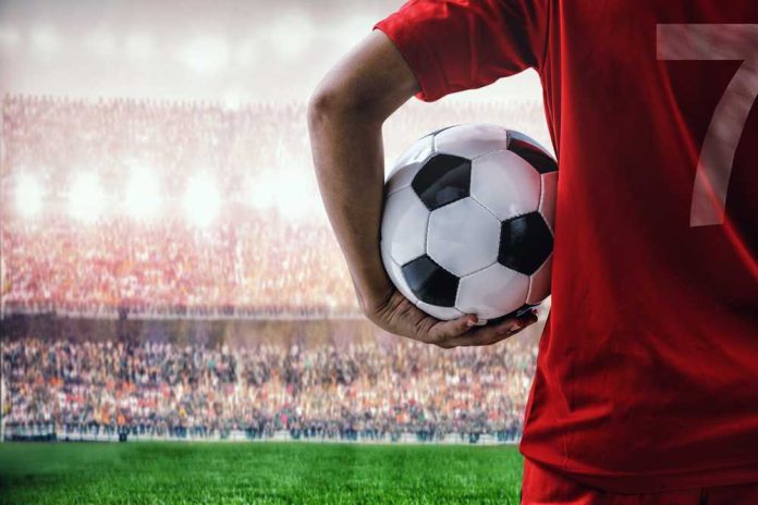 shutterstock_429411850 Soccer player holding a ball in a stadium with a cheering crowd