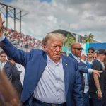Thomas Unleashes 91-Page Broadside Person in blue suit waving at outdoor event.