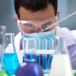 Scientist pipetting blue liquid into test tubes