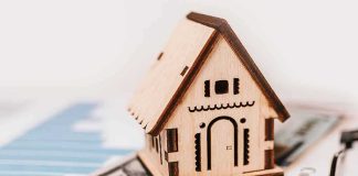 Wooden house model on money and contract papers