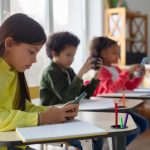 Students using smartphones at classroom desks