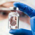Gloved hand holds vial with virus illustration inside
