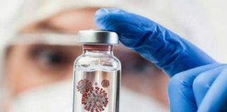 Gloved hand holds vial with virus illustration inside