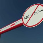 Barrier arm with no abortion sign against blue sky