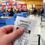 Walmart Slowdown Sparks Wallet Worries Hand holding a store receipt at a supermarket checkout area