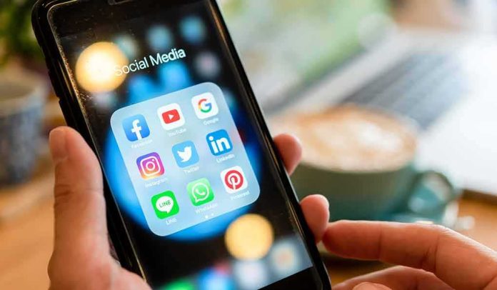 shutterstock_1465631834 Hands holding a smartphone showing social media app icons