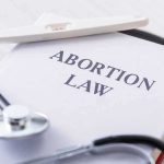 Politicians Out, Consequences In? Pregnancy test and stethoscope on a book titled Abortion Law