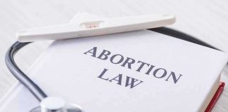 Politicians Out, Consequences In? Pregnancy test and stethoscope on a book titled Abortion Law