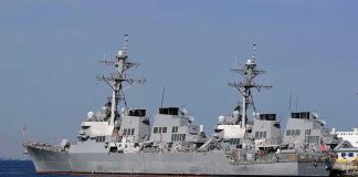 Strait Showdown Rattles Global Trade Three gray naval destroyers docked side by side at a pier