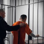 Officer escorting inmate into jail cell