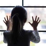 Grim Closet Discovery Spurs Murder Case A child with long hair presses their hands against a window, looking outside