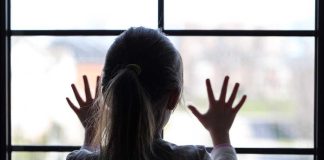 Grim Closet Discovery Spurs Murder Case A child with long hair presses their hands against a window, looking outside