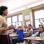 Teacher Shirt Uproar Shakes Colorado District Teacher engaging with students raising hands in a classroom