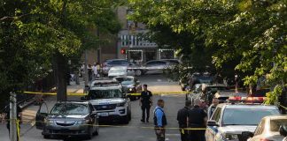 Shot Once—Then Police Opened Fire Police officers secure a residential street with patrol cars and yellow tape