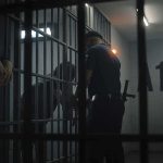 police officer at a jail cell with detainees behind bars