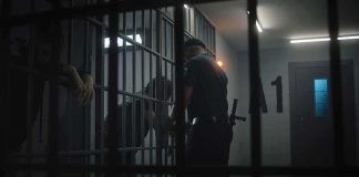 Justice Flip-Flop Leaves Families Fuming police officer at a jail cell with detainees behind bars