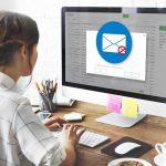 Woman using desktop computer with email warning popup
