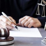 Loaded Gun, Trump Course – Then a Legal Twist Judge writing at desk with gavel and Lady Justice statue
