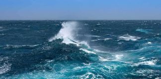 Ocean waves crashing with white spray under a clear blue sky