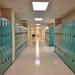 Eight Weeks. Active Investigation. Federal Title IX Probe. School Still Silent. School hallway with rows of teal lockers