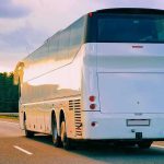 White coach bus driving on a highway at sunset