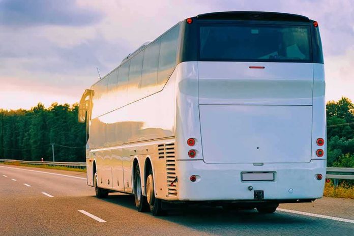 shutterstock_1225299499 White coach bus driving on a highway at sunset